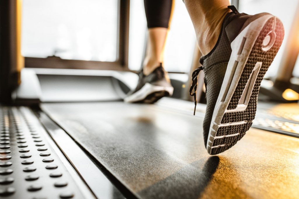 Close up of sole of sneakers of unrecognizable athlete jogging on a treadmill.
